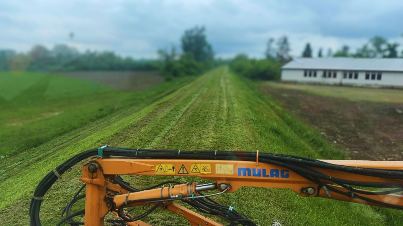 Narandžasti stroj za košenje na zelenoj livadi